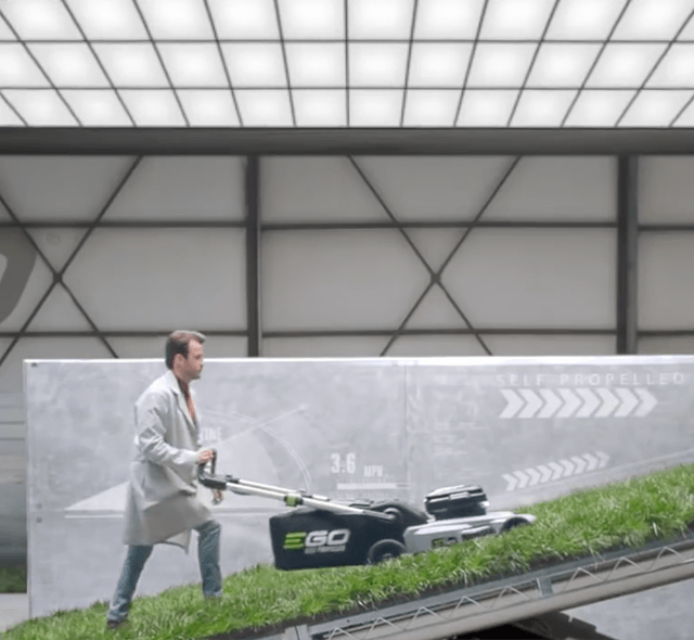 A man in a lab environment testing an EGO Mower on a steep incline.